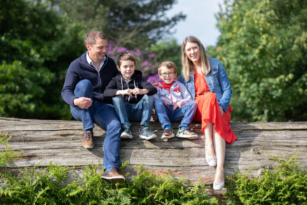 family portrait - mum dad and two children sat on a tree in Knole Park Sevenoaks